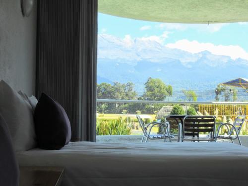 a bedroom with a bed and a large window with a view at Hacienda Panoaya in Amecameca de Juárez