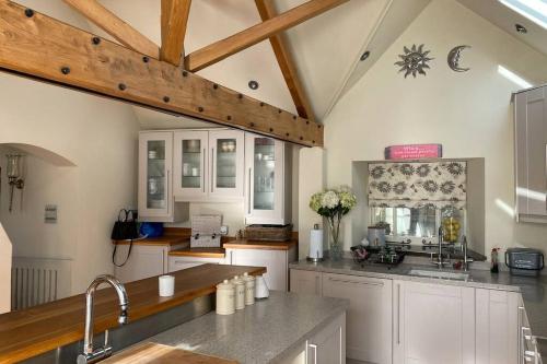 cocina con armarios blancos y techo de madera en Luxury Country Cottage, en Smeeth