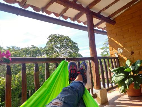 a person laying in a hammock on a porch at Casona CHARA in Barichara