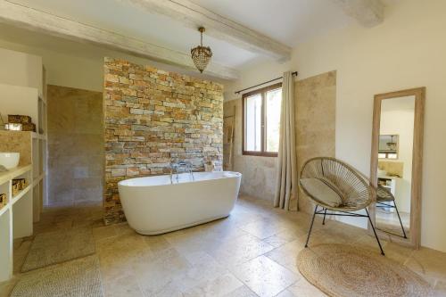 a bathroom with a white tub and a brick wall at Lodge de charme 135m2 avec piscine dans les vignes AOC Bandol à 15 min des plages et du circuit Paul Ricard F1 in Le Beausset