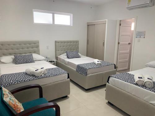 a bedroom with three beds and a chair at Mar de Indias House in Cartagena de Indias