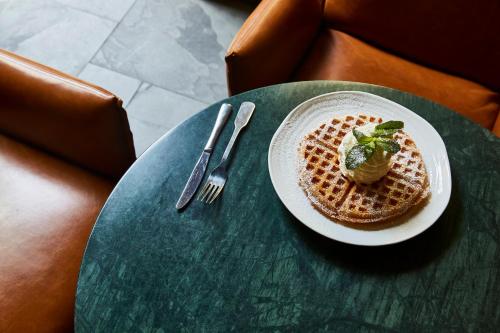 a plate of waffles on a table with a fork and knife at Hotel Indigo Antwerp City Centre by IHG in Antwerp
