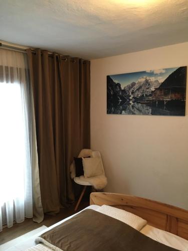 a bedroom with a bed and a chair and a window at Apart Larcher in Arzl im Pitztal