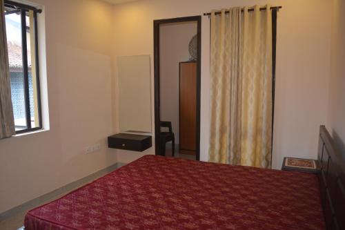 a bedroom with a red bed and a window at Ganga kutir Residency Villa in Raichak