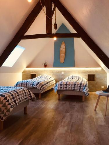 une chambre mansardée avec deux lits et une fenêtre dans l'établissement Pierre et mer au cœur de Saint Cado, à Belz