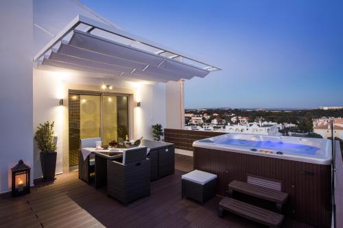 a deck with a hot tub and a table and chairs at D_Loft in Albufeira