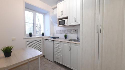 a kitchen with white cabinets and a sink and a table at Apartaments at Pan Kalinovsky in Pyatigorsk