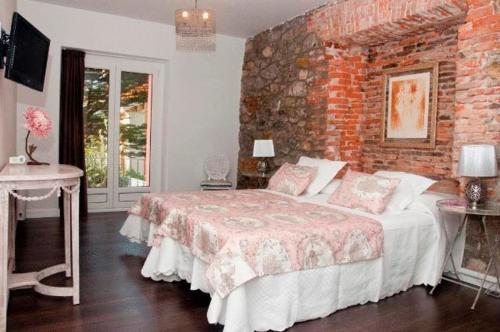 1 dormitorio con cama y pared de ladrillo en Hostal Jardin Secreto, en Santander