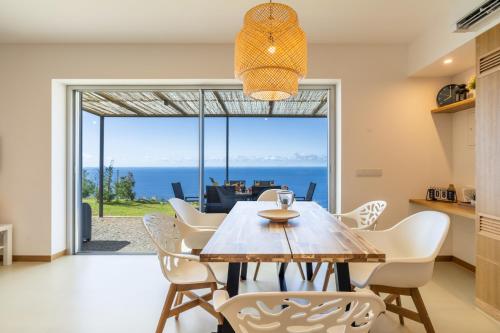 a dining room with a table and chairs with a view at Villa Flora - Nature & Tranquility - Heated pool optional in Jardim do Mar