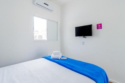 a white bedroom with a bed with a blue blanket at Blue Ocean Suites - Aeroporto Congonhas in Sao Paulo