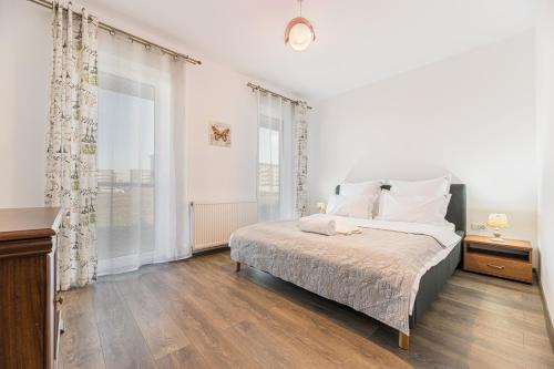 een witte slaapkamer met een bed en een groot raam bij Apartament 2 camere Narcis in Braşov