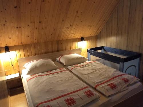 a bed in a wooden room with two pillows at Chata Nika in Ružomberok