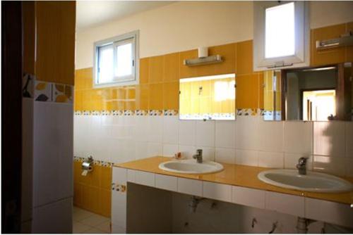 a bathroom with two sinks and two mirrors at Villa Rosa in Dakar