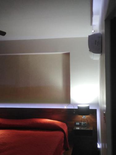 a bedroom with a bed with a red blanket and a lamp at La Mansión del Faro in Tecolutla