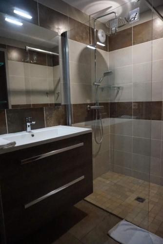 a bathroom with a sink and a shower with a glass door at Domaine des Pierres Jumelles-balade à cheval-chambre d'hôtes Mayenne in Sainte-Gemmes-le-Robert