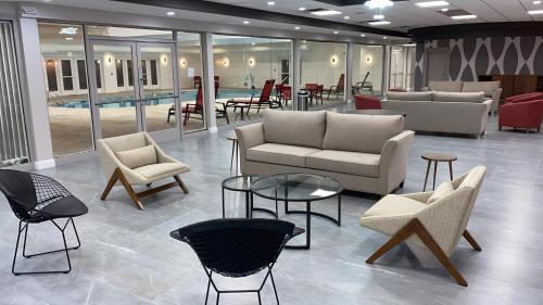 a lobby with couches and chairs and tables and a pool at Ramada by Wyndham Hartford North - Bradley Airport in Windsor Locks