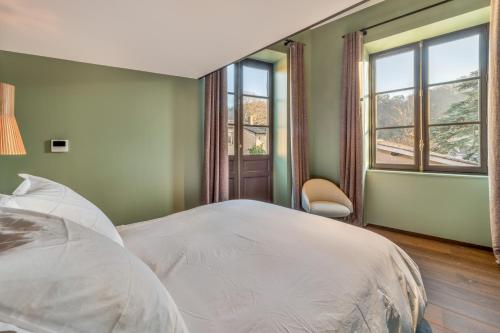 a bedroom with a white bed and two windows at Les Suites de l'Ile Barbe in Lyon