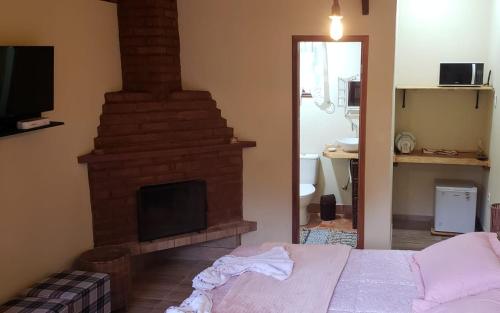 1 dormitorio con chimenea y 1 cama en una habitación en Chalés Canto do Pavão en Visconde De Maua