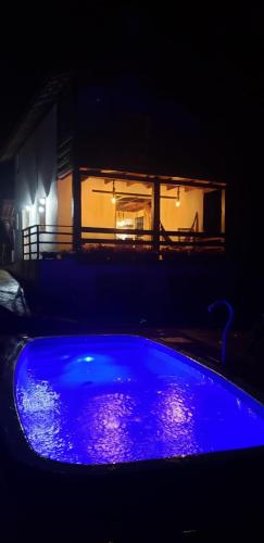 a blue pool in front of a house at night at Chalés Canto do Pavão in Visconde De Maua