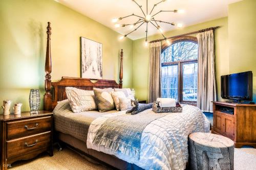 a bedroom with a bed and a tv and a window at Les Manoirs 3bdrs W Pool & Hottub Near Village in Mont-Tremblant