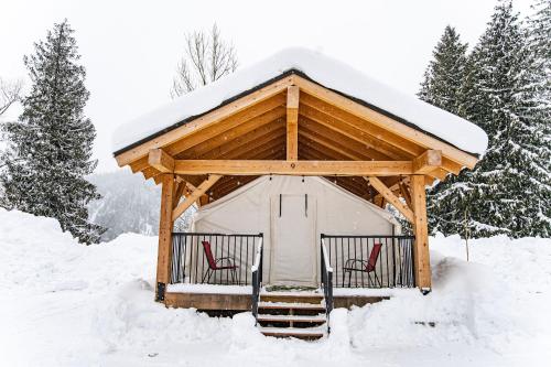 a gazebo with two red chairs in the snow at Boulder Mountain Resort in Revelstoke