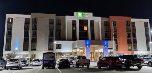 um parque de estacionamento em frente a um hotel à noite em Holiday Inn Express Hotel & Suites Dallas Fort Worth Airport South, an IHG Hotel em Irving
