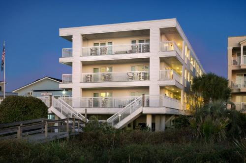 a tall white building with stairs in front of it at Seaside Inn - Isle of Palms in Isle of Palms