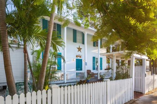 a white house with a white picket fence and palm trees at Kona Kai Oasis in Key West