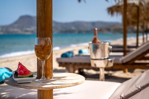 a glass of wine and a piece of watermelon on a table near the beach at Akti Galinis in Kalyves
