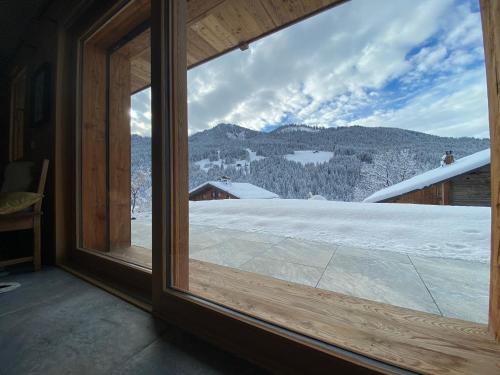 a window with a view of a snowy mountain at CHALET LYOBA in Le Grand-Bornand