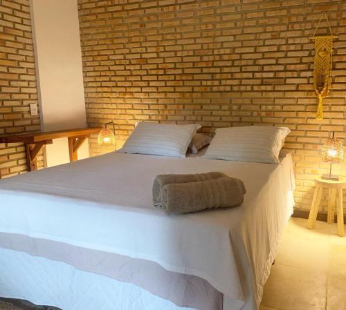 een slaapkamer met een groot wit bed met een bakstenen muur bij BEACH HOUSE - Suite 2 - NA PRAIA -BEACHFRONT in Barra Grande