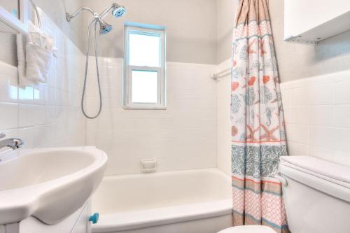 uma casa de banho branca com um lavatório e uma cortina de chuveiro em Tropic Terrace #49 - Beachfront Rental condo em St. Pete Beach