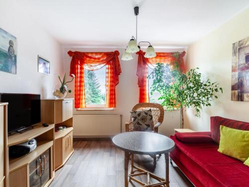ein Wohnzimmer mit einem roten Sofa und einem Tisch in der Unterkunft Apartment in Lichtenhain with mountain views in Lichtenhain