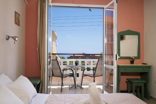 a bedroom with a bed and a balcony with a table at Theodora Studios & Apartments in Skala