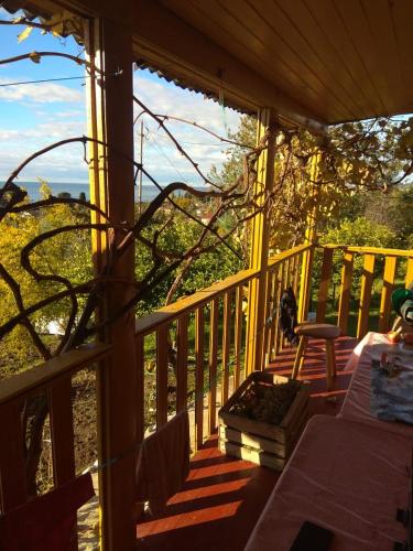un porche de madera con una mesa y una silla. en Небольшой Домик в Абхазии в 6 минутах от моря с прекрасным видом en Novy Afon