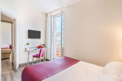 a hotel room with a bed and a desk and a window at Best Western Hotel du Roy d'Aragon in Bonifacio