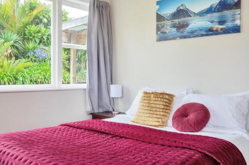 um quarto com uma cama com um cobertor vermelho e uma janela em Sunny & Cozy Home near Western Springs em Auckland