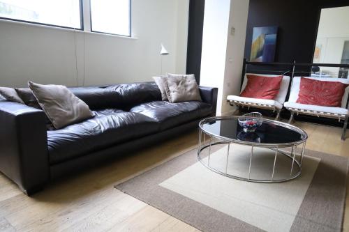 sala de estar con sofá de cuero negro y mesa de cristal en The Walkup Southbank, en Melbourne