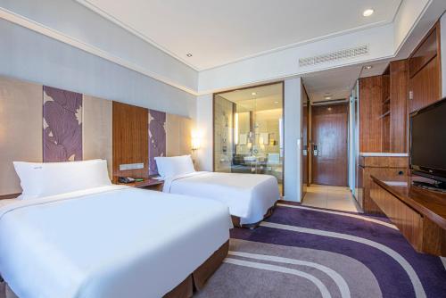 a hotel room with two beds and a television at Holiday Inn Qingdao City Center, an IHG Hotel - May 4th Square in Qingdao