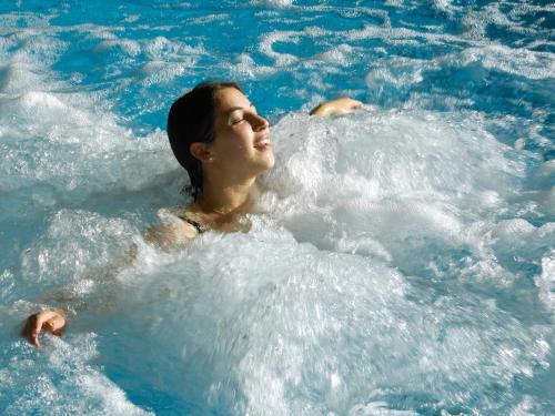 a woman is swimming in a pool of water at Wellnesshotel Linde in Sulzberg