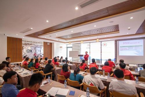 a group of people sitting at tables in a room with a presentation at Le's Cham Hotel in Nha Trang