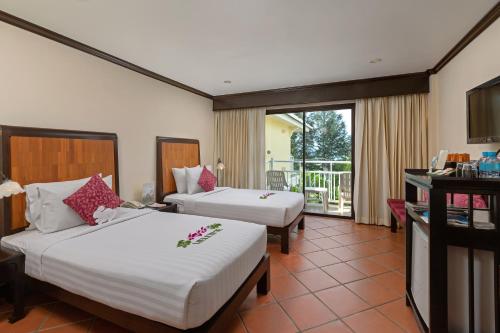 a hotel room with two beds and a balcony at The Front Village - SHA Plus in Karon Beach