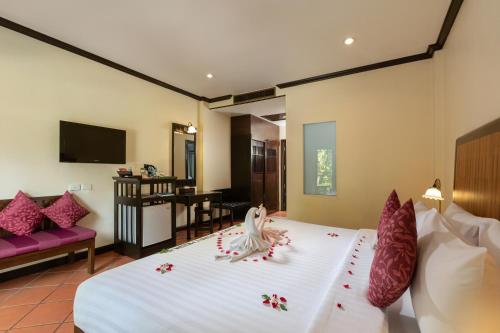 a hotel room with a bed with flowers on it at The Front Village - SHA Plus in Karon Beach