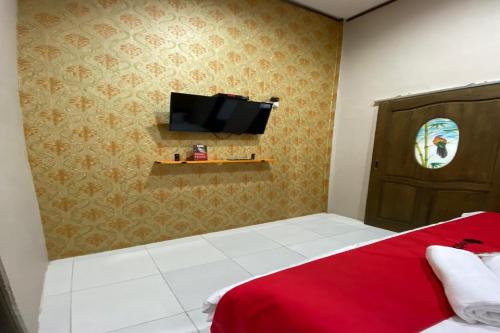 a bedroom with a red bed and a flat screen tv at RedDoorz near Mojokerto Train Station in Soko