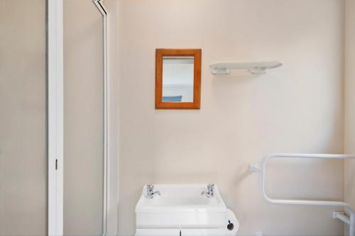 uma casa de banho com um lavatório branco e um espelho. em Blue Bach - Omori Holiday Home em Kuratau