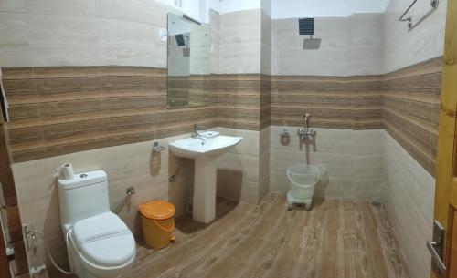 a bathroom with a toilet and a sink at Hotel Sarla Regency in Kulu