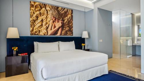 a bedroom with a white bed and a painting on the wall at PIER 57 - 211 Luxurious & Modern 1 BR Romantic Zone in Puerto Vallarta