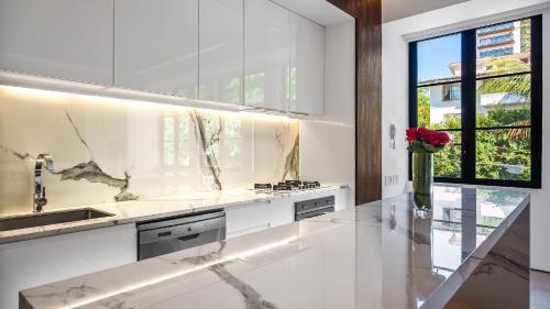 a white kitchen with a sink and a vase of roses at PIER 57 - 211 Luxurious & Modern 1 BR Romantic Zone in Puerto Vallarta