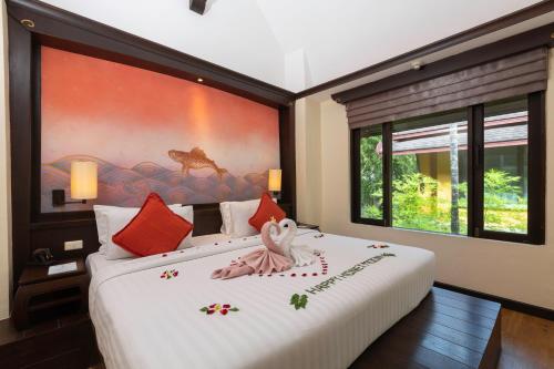 カロンビーチにあるThe Village Resort & Spa - SHA Plusの大きな絵画が飾られたベッドルーム1室
