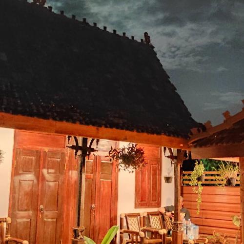 een huis met houten deuren en stoelen op een patio bij Omah Kampong in Yogyakarta